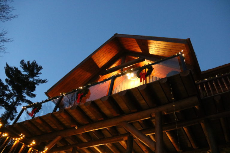 view upwards of log cottage deck with lights at Quebec cottage rental