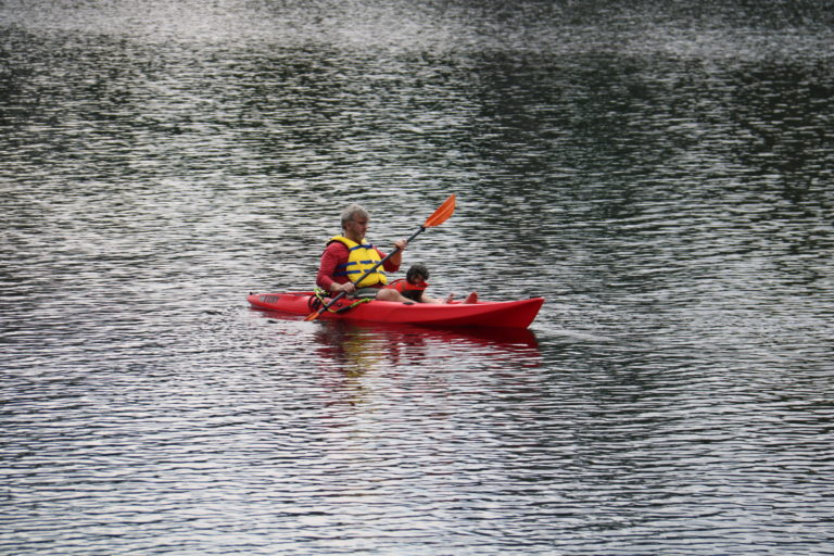 man and dog kayaking quebec lake cottage