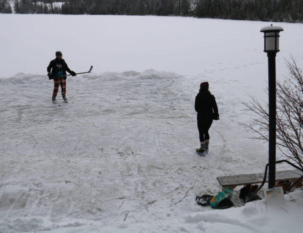 two kids playing ice hockey on lake