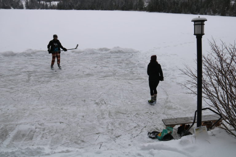 two kids playing ice hockey on lake