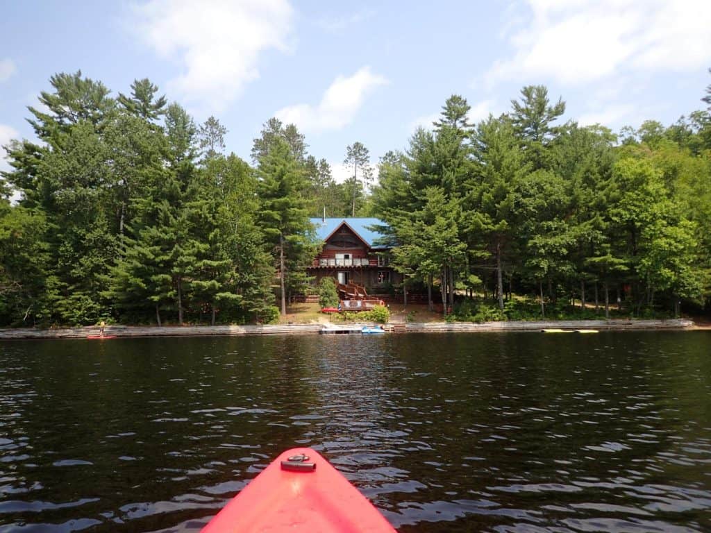 log cottage by lake with red kayak